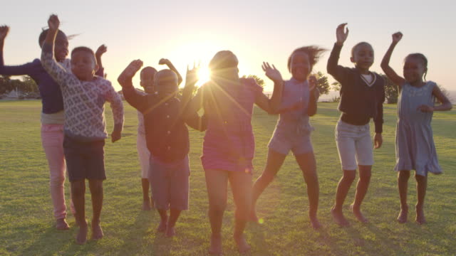 Elementary-school-kids-jumping-outdoors-at-sunset