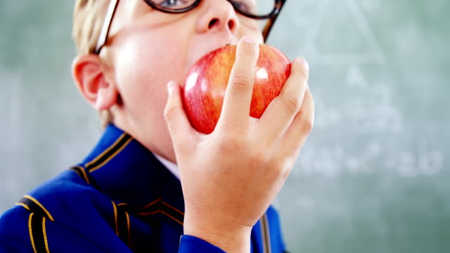Schoolboy-eating-apple-in-classroom