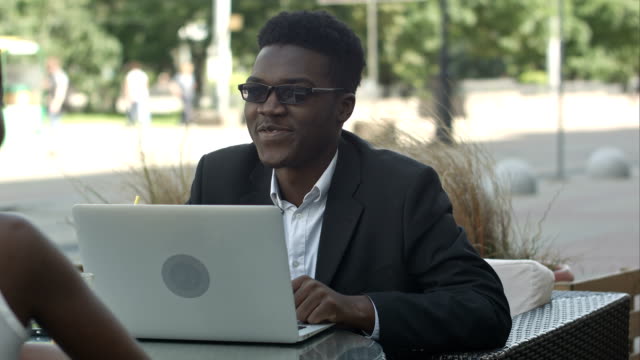 Afrikaner,-die-Geschäftsstrategie,-seine-afrikanischen-Kollegin-mit-Laptop-bei-Treffen-in-einem-Café-zu-erklären