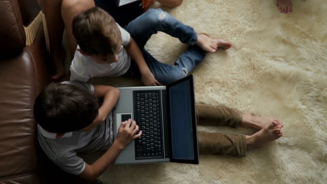 Dos-juegos-de-los-niños-en-portátil-sentado-en-la-alfombra-en-su-casa