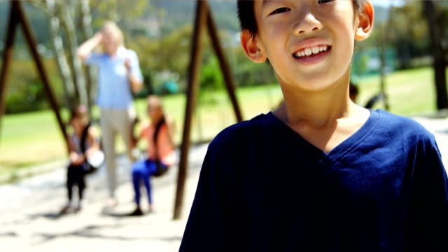 Portrait-of-happy-schoolboy-standing-in-playground