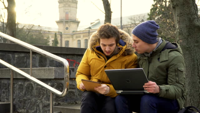 Students-with-laptop-and-tablet-in-park