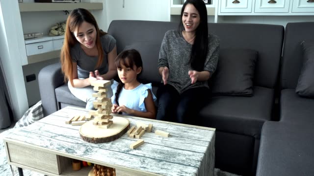 Young-girl-playing-game-with-mother-and-asian-nanny-in-living-room.