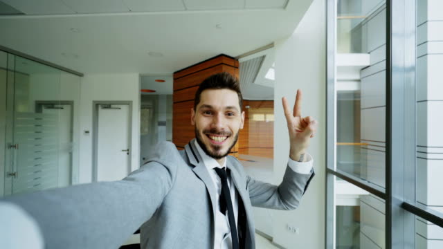 POV-jungen-Geschäftsmann-im-Anzug-Selfie-fotografieren-und-amüsieren-Sie-sich-im-modernen-Büro