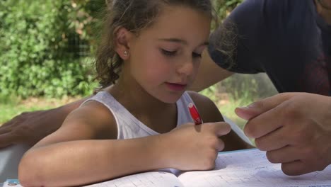 Young-girl-in-summer-camp-doing-homeworks-outside-outdoor-in-park-under-trees-sitting-on-table-slow-motion