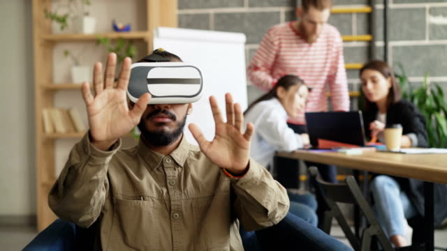 Afrikanische-amerikanische-Mann-VR-Simulator-in-Spielentwicklung-Büro-testen.-Start-up-kreativ-Team-diskutieren-zukünftige-virtual-Reality-Technologie-Projekt