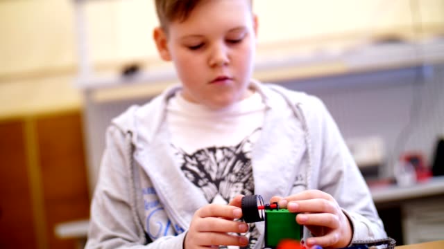 el-niño-de-11-años,-juega-en-el-diseñador-de-cubos,-placas,-circuitos,-cables.-un-pequeño-inventor-crea-robots,-máquinas-de-diferentes-partes-del-diseñador