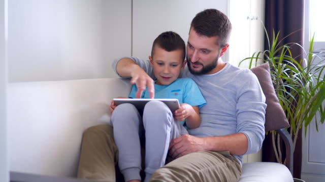 Entspannte-Vater-mit-seinem-Sohn-etwas-auf-dem-tablet