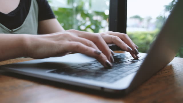 Eine-Frauenhand-arbeiten-und-tippen-auf-Laptoptastatur-auf-Holztisch
