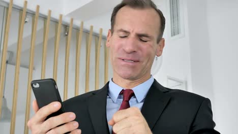 Tense-Upset-Middle-Aged-Businessman-Reacting-to-Loss-on-Smartphone