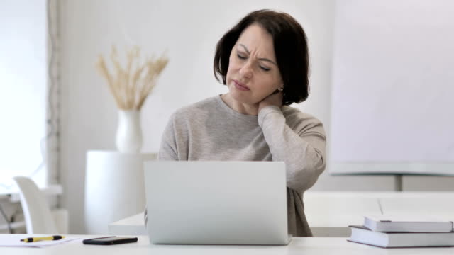 Mujer-Senior-cansado-con-dolor-de-cuello-trabajando-en-ordenador-portátil