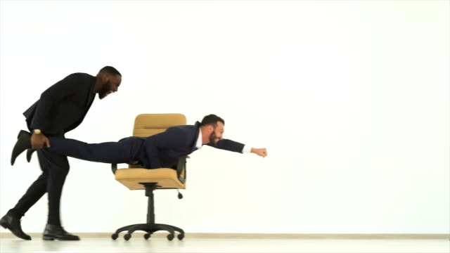 The-two-happy-businessmen-playing-with-an-office-chair.-slow-motion