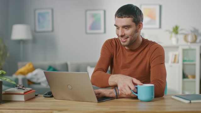 Retrato-de-sonriente-guapo-trabajando-en-ordenador-portátil,-sentado-en-su-escritorio-de-madera-en-casa.-Hombre-navegando-por-Internet,-trabajando-en-la-Notebook-de-su-sala-de-estar.