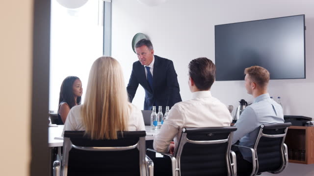Reifen-Sie-Geschäftsmann-Adressierung-Fraktionssitzung-Tisch-am-Graduate-Recruitment-Assessment-Tag