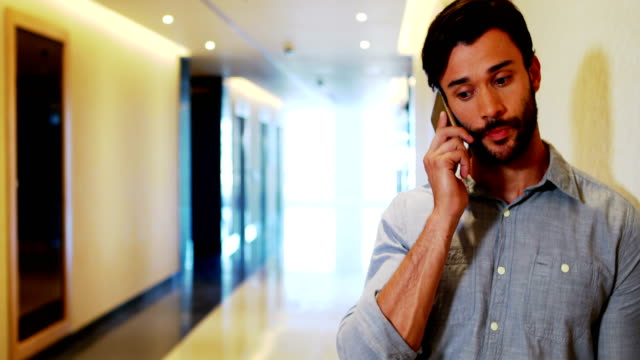 Männliche-Executive-telefonieren-mit-Handy-im-Korridor