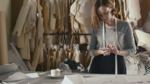 El-diseñador-de-ropa-femenina-está-fotografiando-patrones-de-costura-con-un-teléfono-inteligente-en-una-mesa-de-estudio.