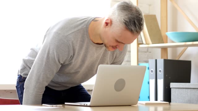Mann-mittleren-Alters-kommen-zur-Arbeit,-beginnt-auf-Laptop