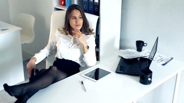 Erfolgreiche-Business-Frau-im-Büro-mit-ihren-Füßen-auf-dem-Schreibtisch