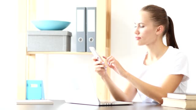 Mujer-mediante-aplicaciones-para-teléfonos-inteligentes-en-el-trabajo-en-oficina