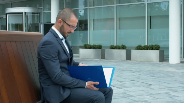 A-Businessman-Checking-Important-Documentation-In-Front-Of-Office-Building