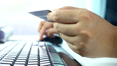 Closeup-of-woman's-hands-holding-a-credit-card-and-using-computer-for-online-shopping-in-workspace