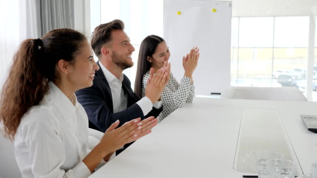 managers-smile-and-clap-at-Table-in-business-center,-happy-business-group-clapping-hands-in-slow-motion
