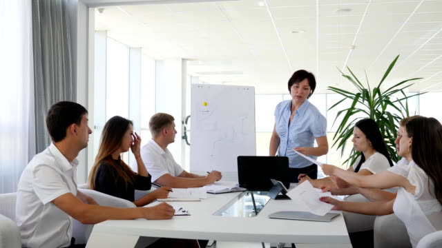 group-of-people-into-office-clothes-at-desk-and-mentor-near-Whiteboard-in-Business-center