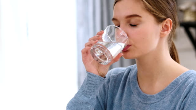 Hermosa-mujer-bebiendo-agua-de-vidrio-en-casa