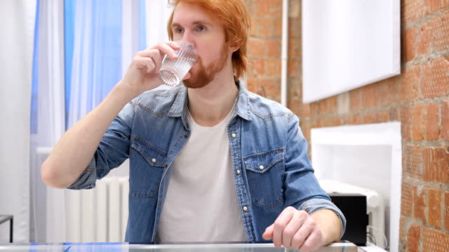 Portrait-of-Young-Redhead-Beard-Man-Drinking-Water-from-Glass