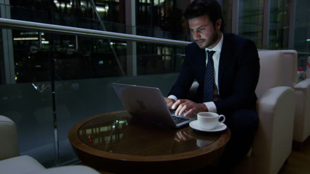 Arabic-businessman-hotel-atrium-night-using-laptop-computer