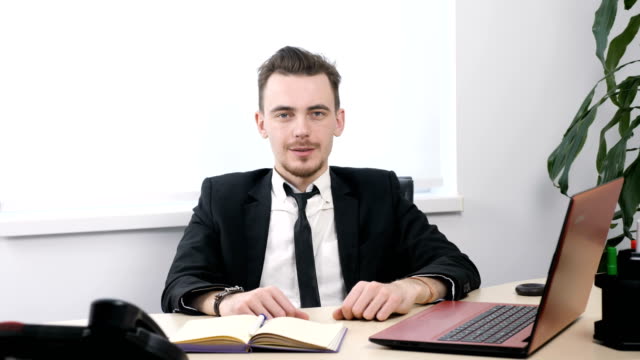 Young-businessman-in-suit-sitting-in-office-and-showing-thumbs-up-sign-60-fps