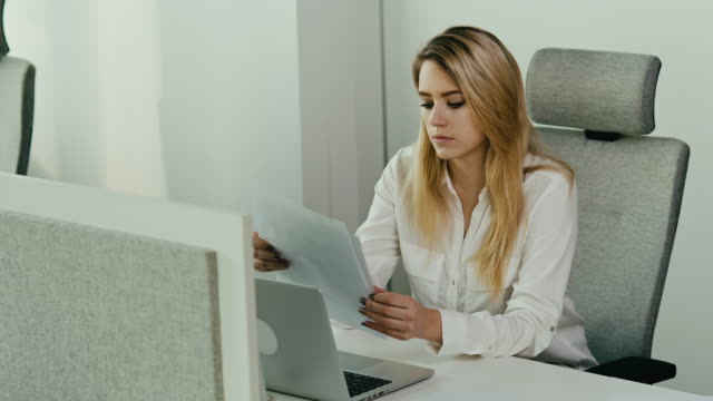 junge-Geschäftsfrau-sucht-nach-Dokumenten-in-einem-hellen-Büro
