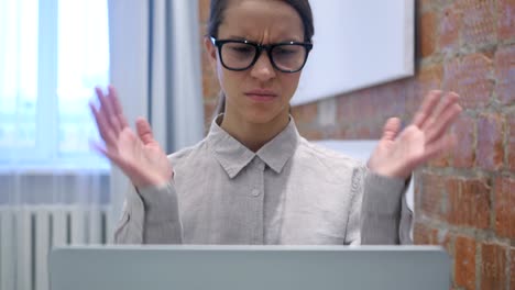 Hispanic-Woman-Upset-by-Loss-while-Working-on-Laptop