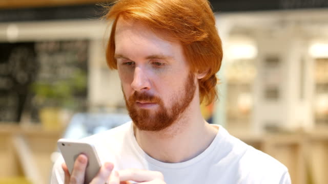 Redhead-Beard-Man-Using-Smartphone-for-Online-Browsing