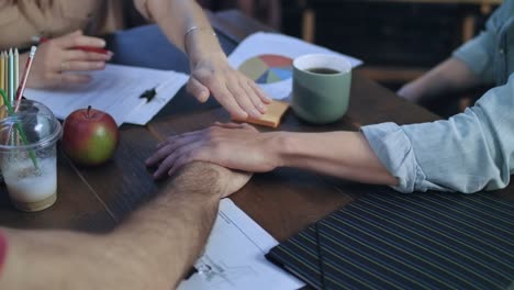 Geschäftsleute,-indem-ihre-Hände-auf-einander-auf-Tisch-für-Teamarbeit