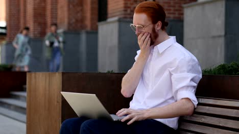 Astonished-Designer-Wondering-while-Using-Laptop-Sitting-on-Bench