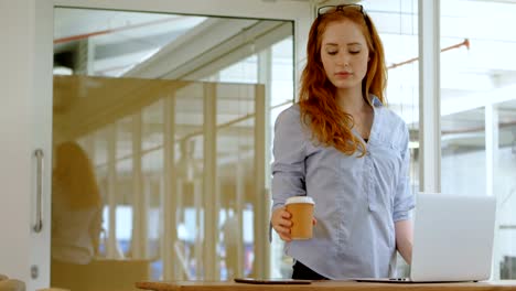 Mujer-ejecutiva-tomar-café-durante-el-uso-de-laptop-en-la-oficina-4k