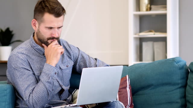 Pensive-Man-Working-on-Laptop-in-Bedroom