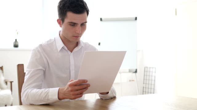 Businessman-Reading-Contract-Papers-in-Office