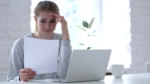 Young-Woman-Reading-Document-and-Gets-Upset-for-Loss