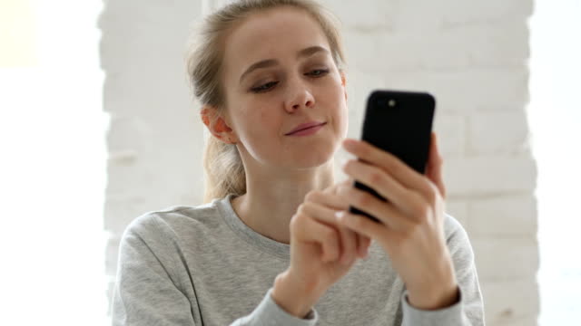 Young-Woman-Browsing-on-Smartphone-in-Loft-Workplace