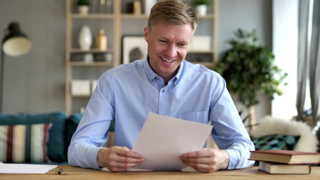 Businessman-Excited-after-Reading-Contract-Papers-at-Work