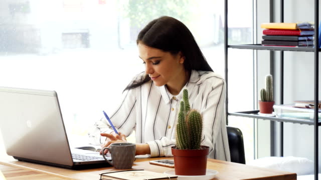 Attractive-young-businesswoman-enjoying-working-at-her-office