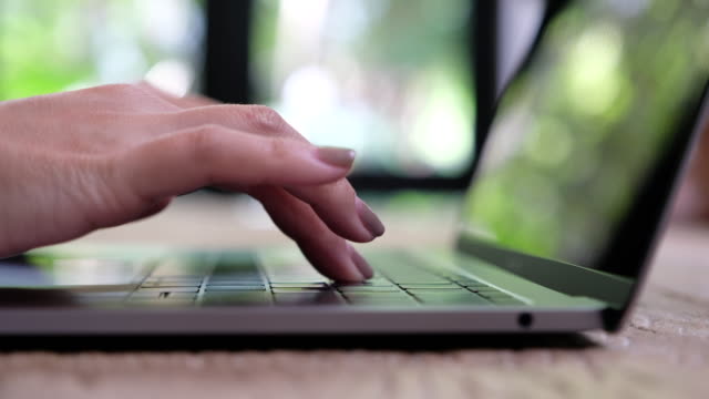 A-woman's-hands-working-and-typing-on-laptop-keyboard-on-wooden-table