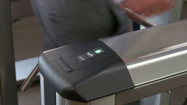 Hands-of-people-apply-electronic-pass-to-turnstile-wicket-checkpoint-in-office.