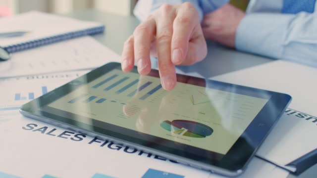 Businessman-Using-Digital-Tablet-Over-Sales-Documents-At-Desk-4K