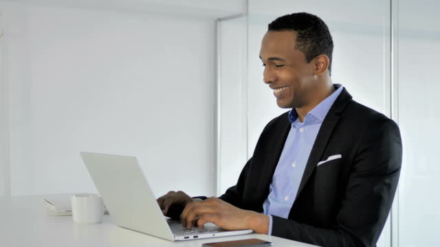 Ocasional-empresario-afroamericano-celebrando-éxito,-trabajando-en-ordenador-portátil