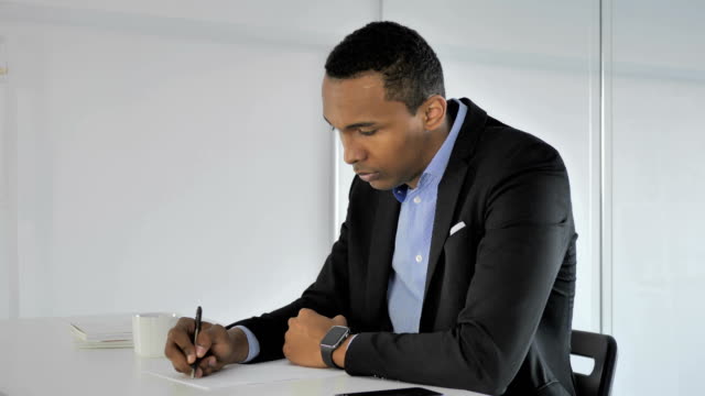 Casual-Afro-American-Businessman-Writing-at-Work,-Paperwork