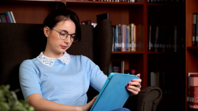 junge-attraktive-Geschäftsfrau-mit-Tablet-PC-im-Librory-Office-Bücherregal-Hintergrund