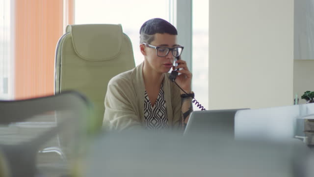 Mujer-de-negocios-hablando-por-teléfono-y-el-uso-del-ordenador-portátil